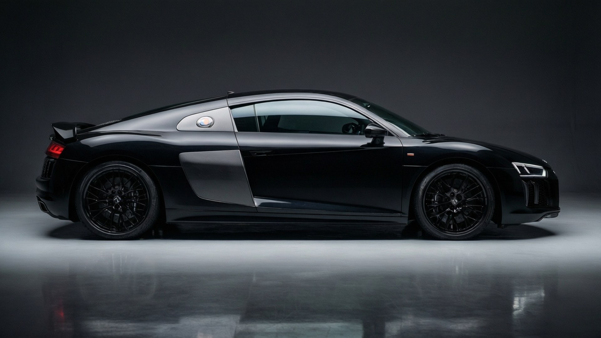 Siyah bir Audi R8, temiz bir stüdyo ortamında çekilmiş, şık tasarımını vurguluyor.