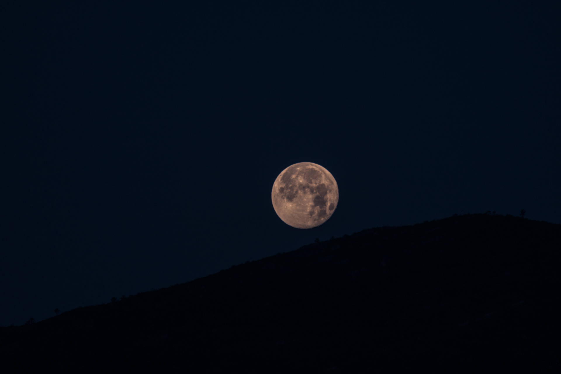 Tepelerin üzerinde parlak bir şekilde parlayan dolunay. Ay ve yaylaların minimalist fotoğrafı.