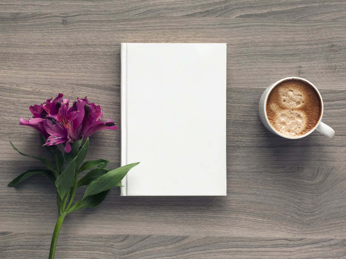 Beyaz bir kitap ve ahşap bir masanın üzerinde bir fincan kahve Duvar Kağıdı