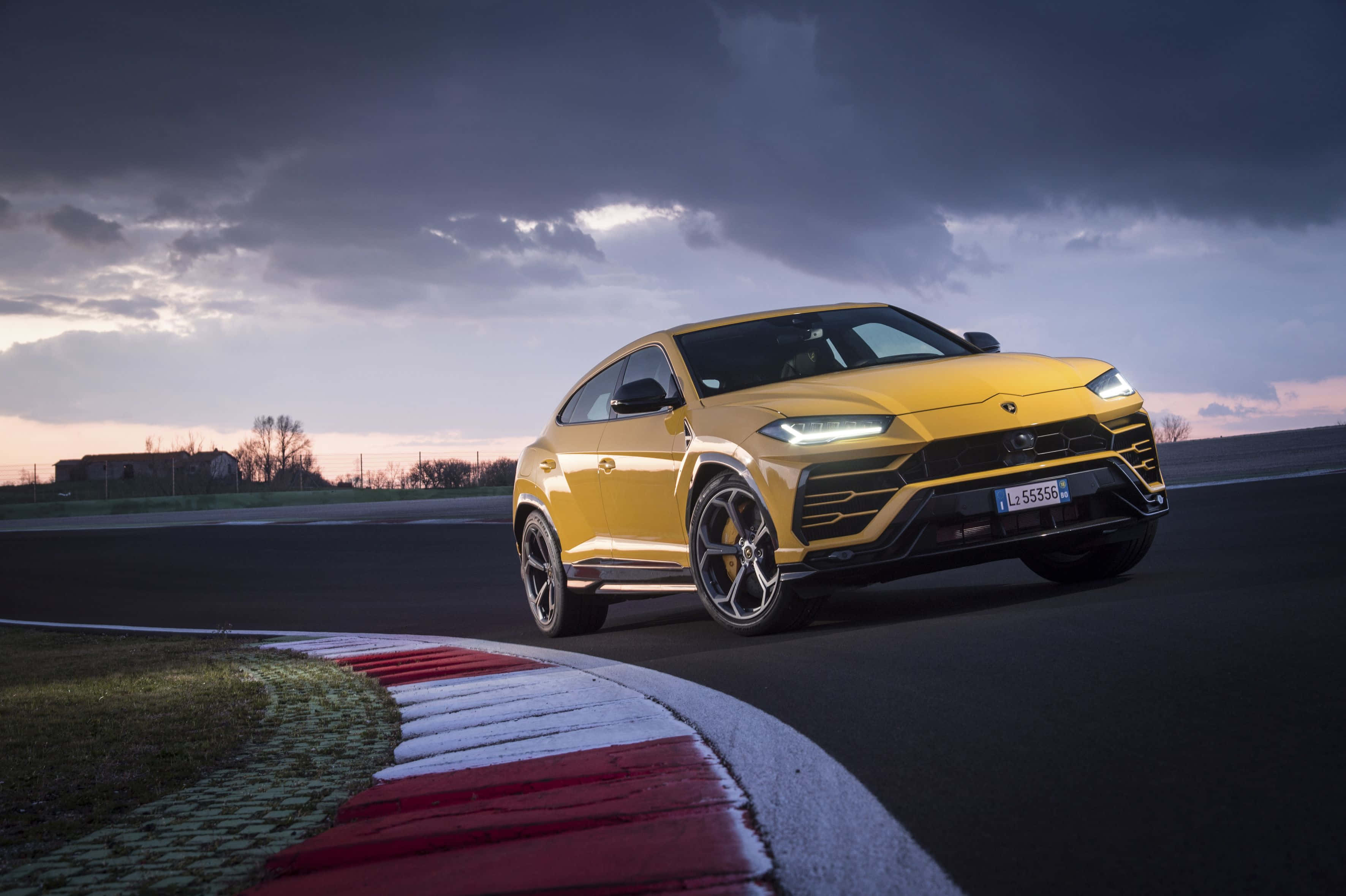 lamborghini urus - sarı bir SUV pistte sürüş yapıyor Duvar Kağıdı