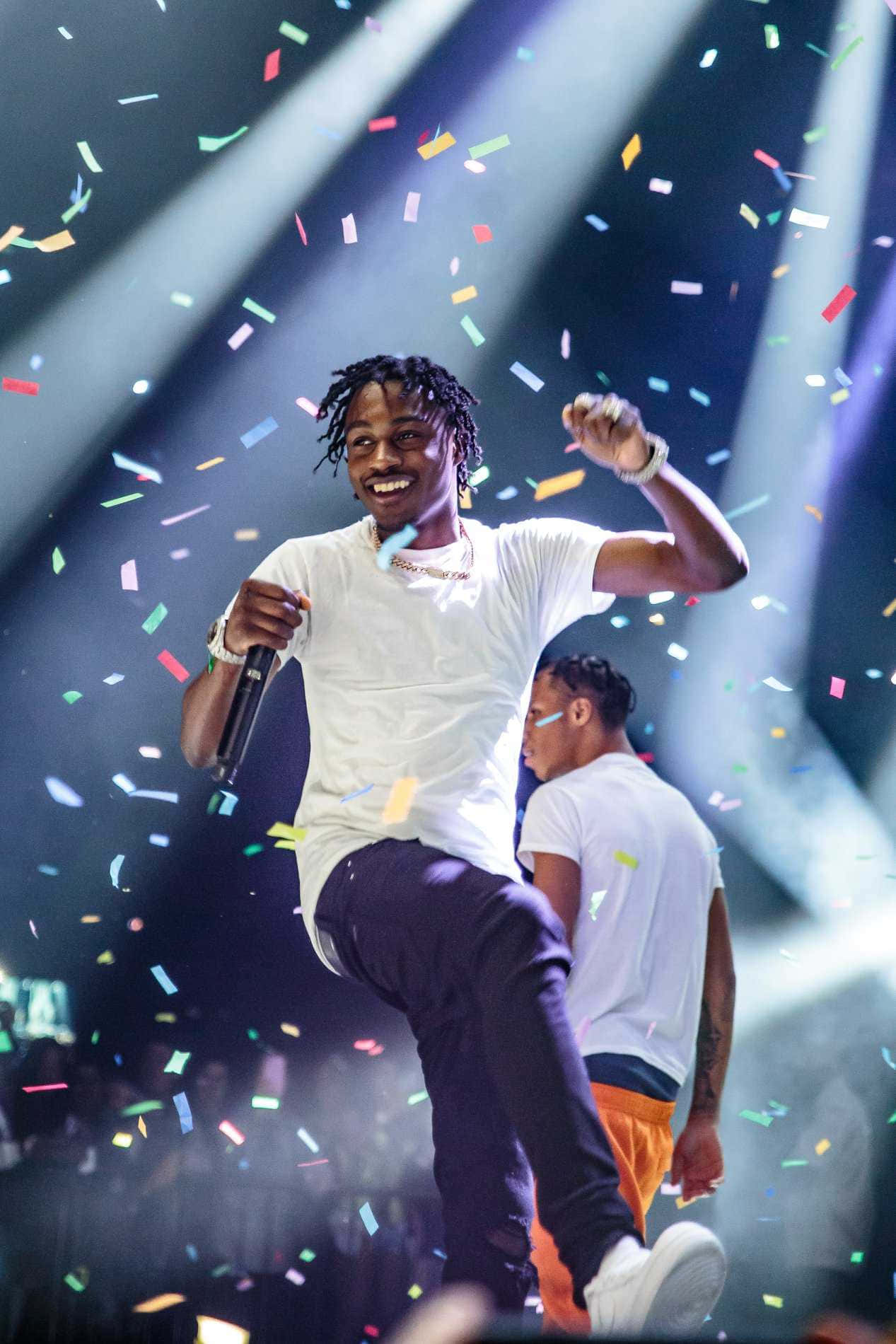 Lil Tjay loş bir ortamda şık bir şehirli kıyafetle poz veriyor Duvar Kağıdı