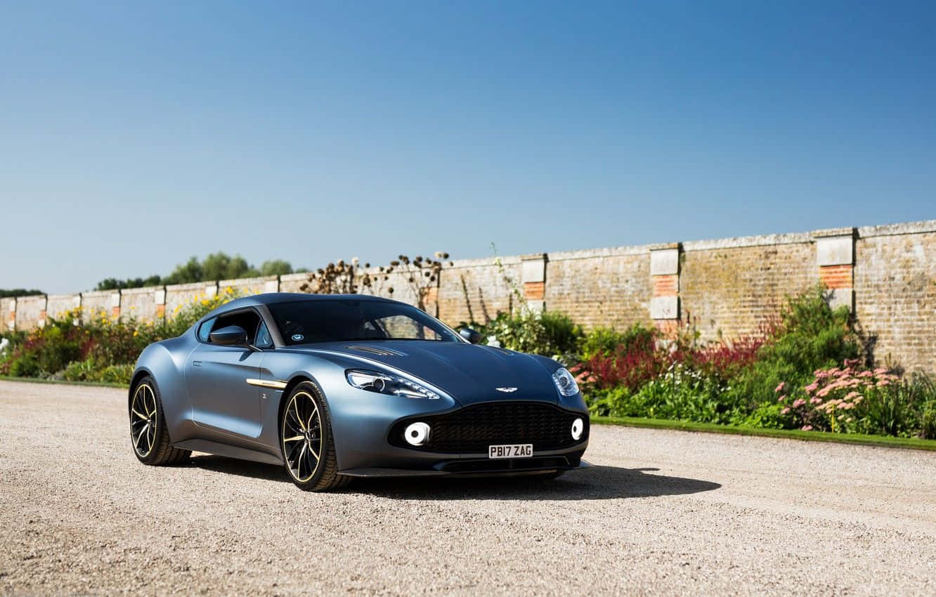 Manzaralı Bir Yolda Hareket Halindeki Çarpıcı Aston Martin Vanquish Duvar Kağıdı