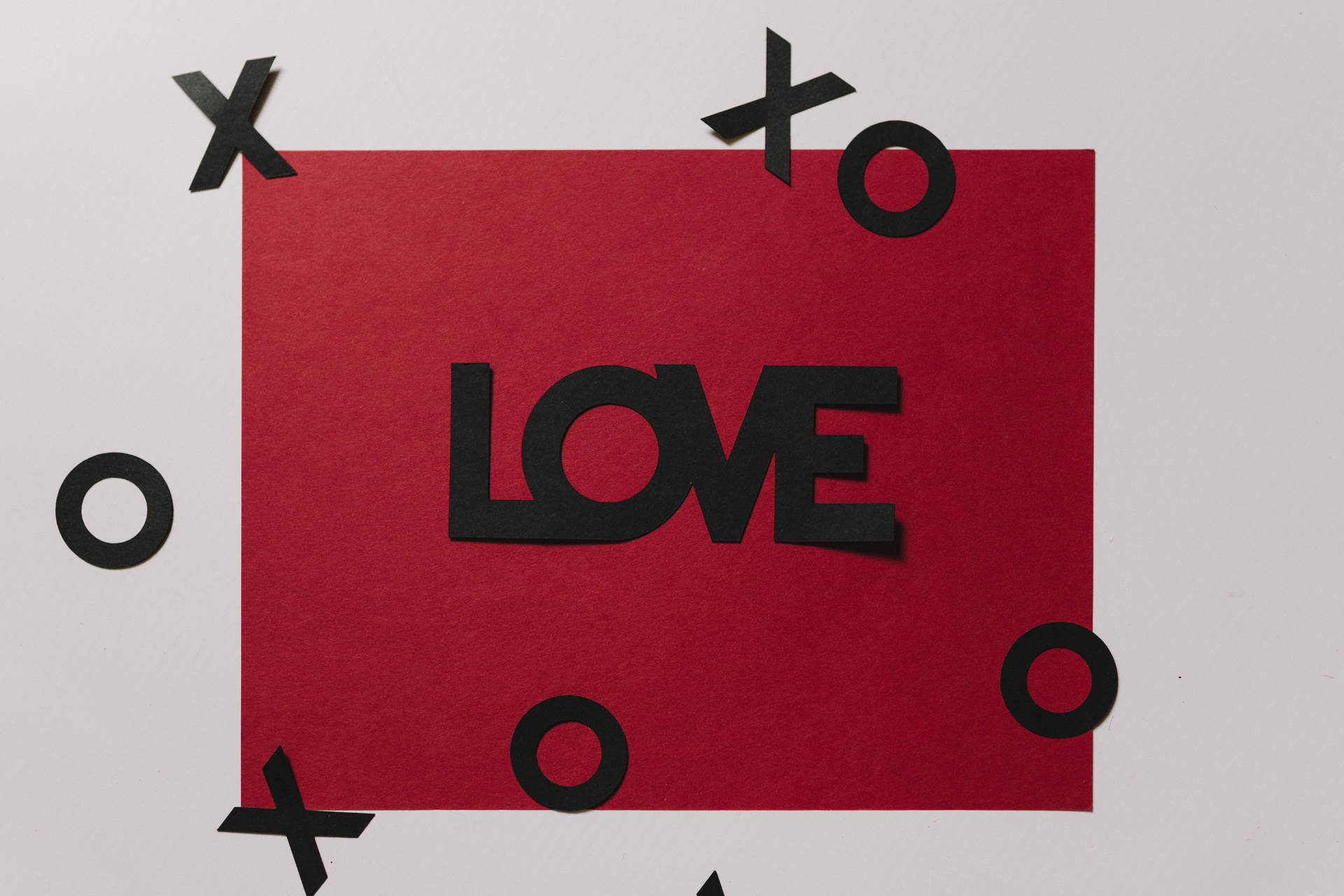Beyaz yüzeyde 'Love' yazısı siyahla ve yüzen XOXO kesikleriyle birlikte kırmızı aşk mektubu.