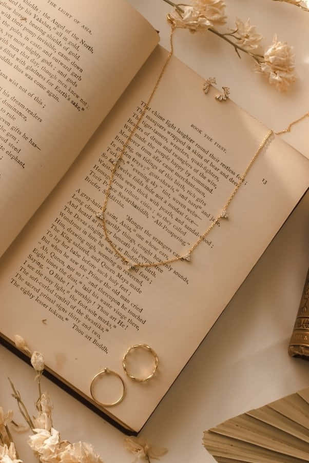 Üzerinde kolye ve yüzük olan bir kitap Duvar Kağıdı
