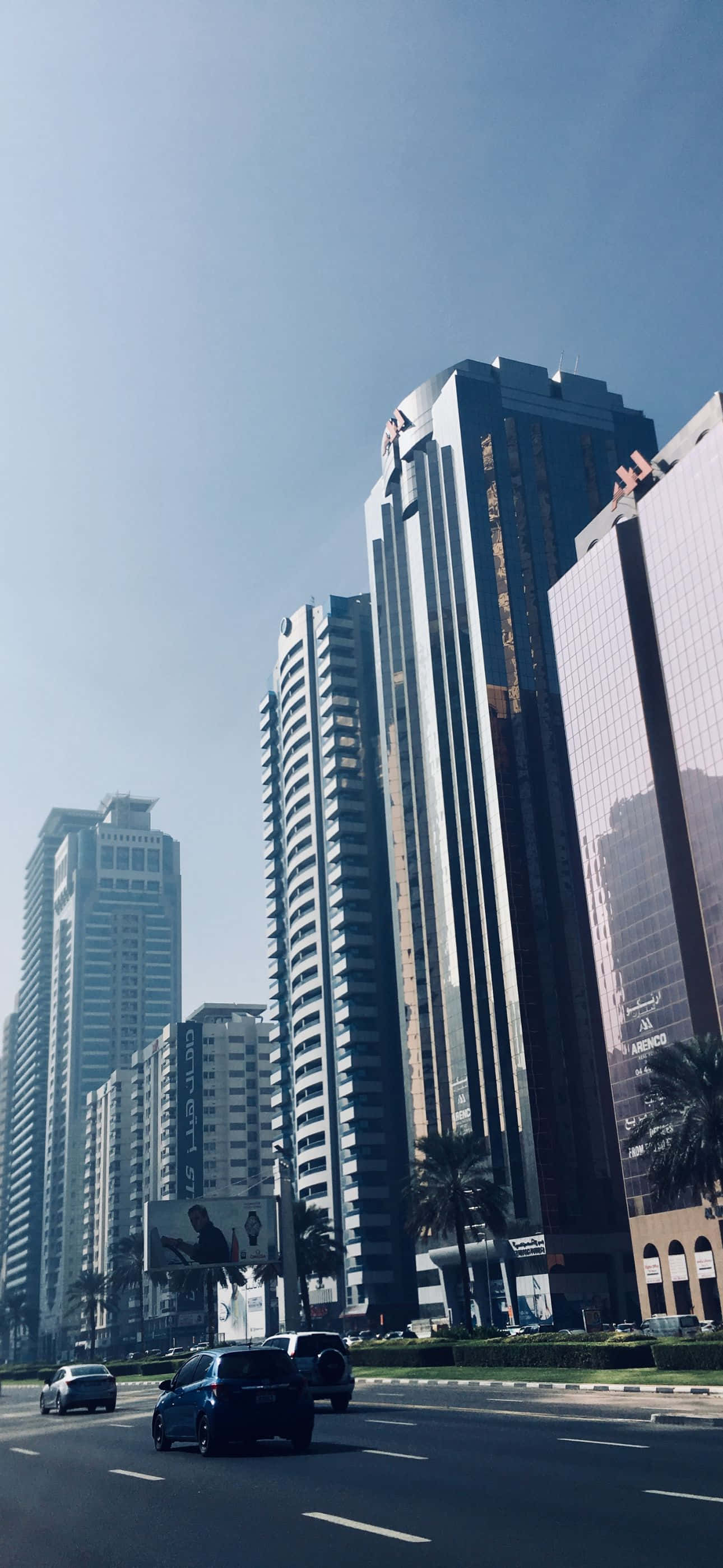 yüksek binaları ve caddede araba kullanan arabaları olan bir şehir Duvar Kağıdı
