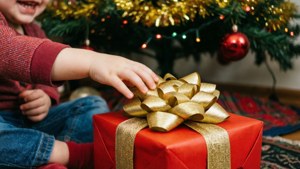 Bir çocuğun eli, Noel ağacının altındaki kırmızı hediyeye uzanıyor. — Noel Hediyeleri Duvar Kağıdı