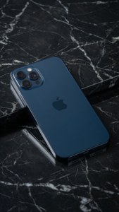 Mermer üzerinde gece yarısı mavisi iPhone 17, minimalist stüdyo çekimi.