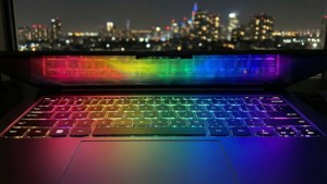 Chromebook'un gökkuşağı renklerinde arkadan aydınlatmalı klavyesinin ve gece şehir manzarasının yakın çekimi.