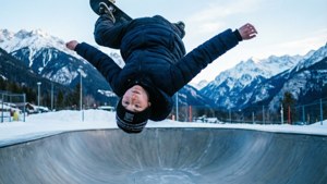 Karlı dağ ortamında halfpipe'de 360 dönüş yapan kaykaycı çocuk.