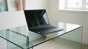 Cam bir masanın üzerinde bir Chromebook ile temiz, minimalist bir sahne.