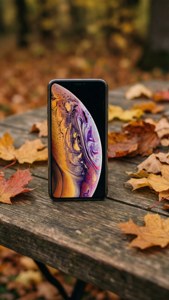Ahşap bir masanın üzerinde sonbahar yapraklarıyla birlikte bir iPhone XR, sıcak ve rustik bir atmosfer. — iPhone XR Duvar Kağıdı